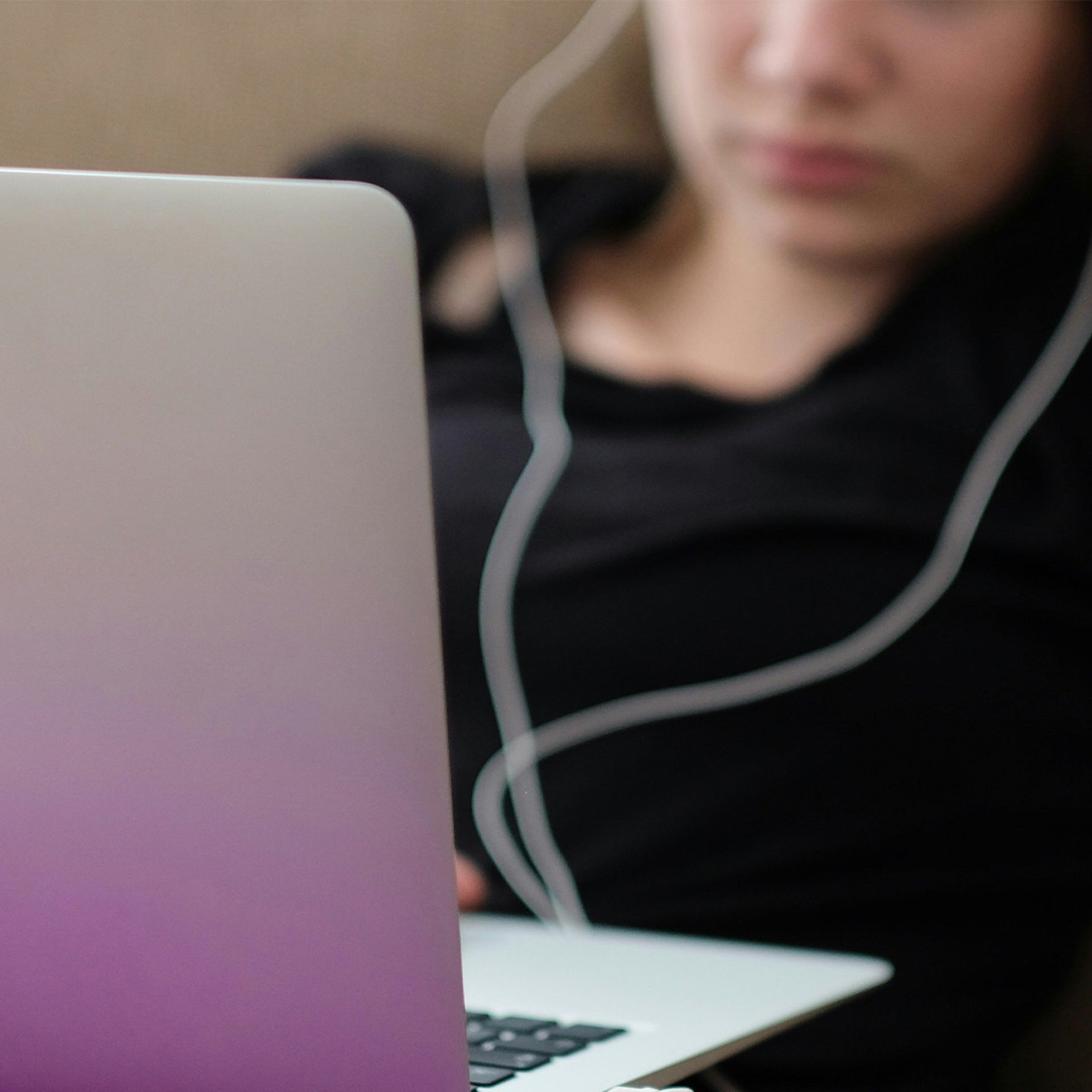 Woman looking at a laptop screen while earbuds are in her ear